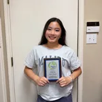 Vivian holding her Gloria Barron Prize plaque